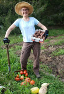 Heidi poses with potatoes, tomatoes and squash from her garden.